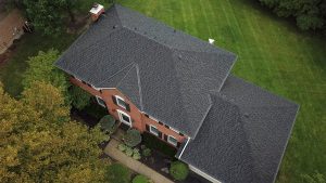 Aerial view of a black asphalt shingle roof on a large brick home