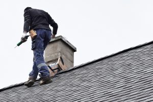 Professional roofer inspecting the grey slate shingles roof of a home